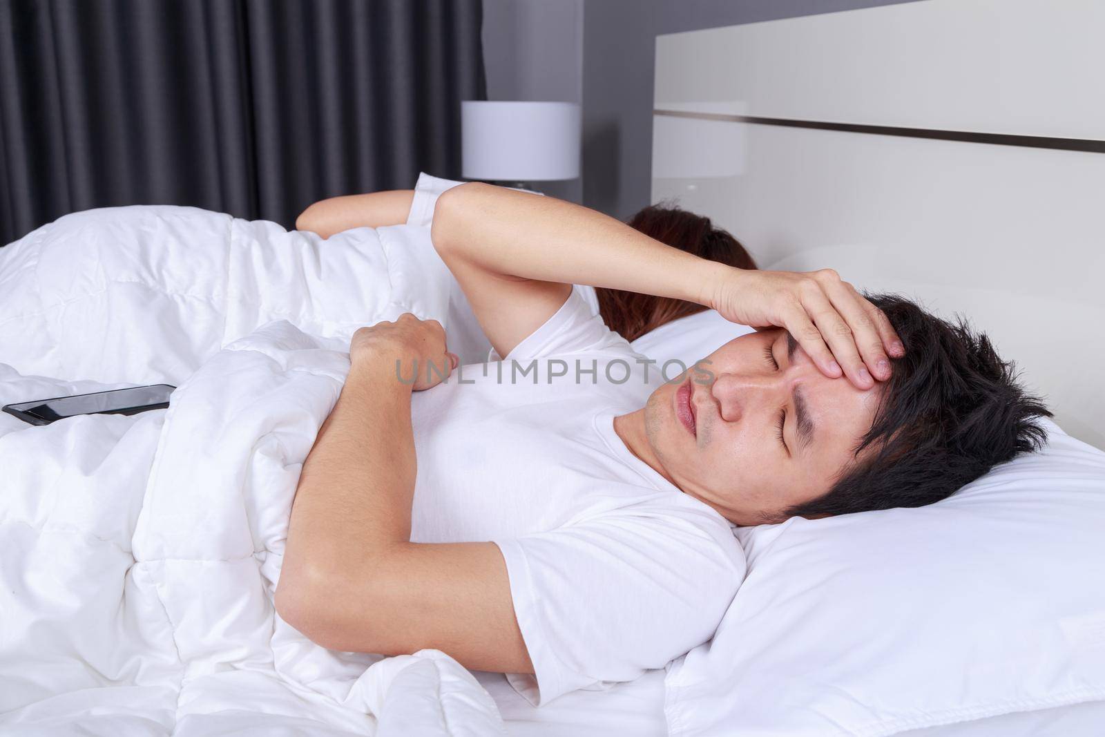 man having sleepless on bed and having migraine,stress, insomnia, hangover in the bedroom