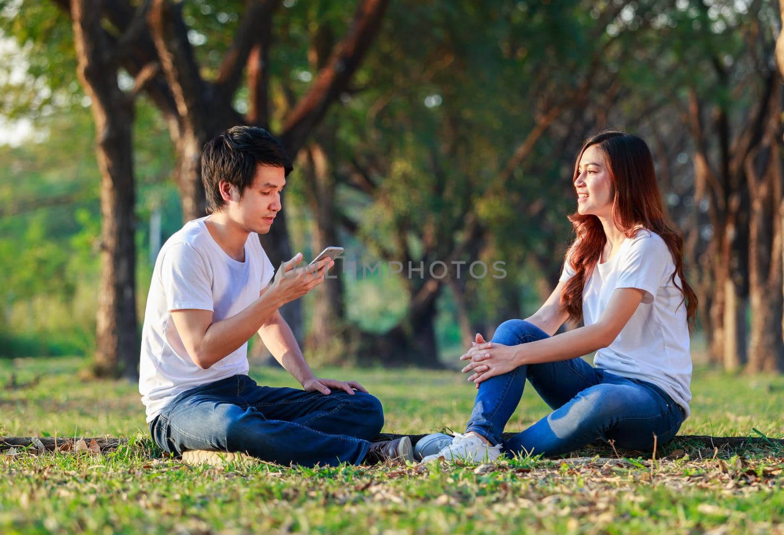 couple talking and using mobile phone in park by geargodz