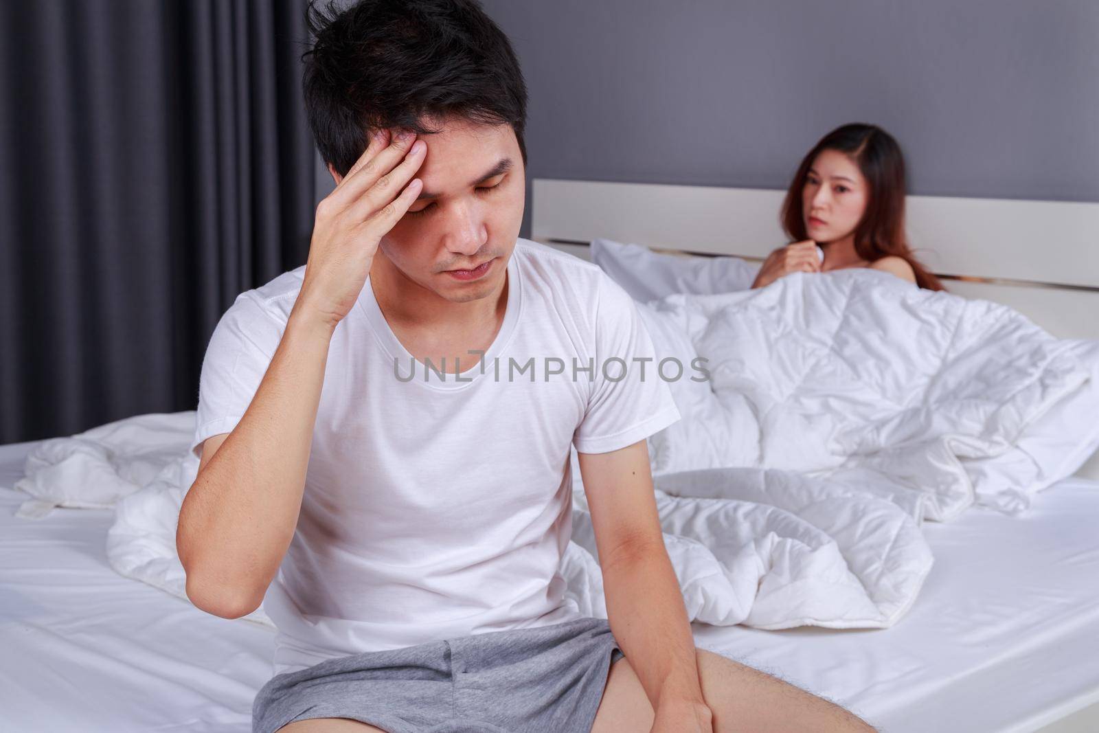 upset man having problem sitting on the bed with his wife in the bedroom by geargodz