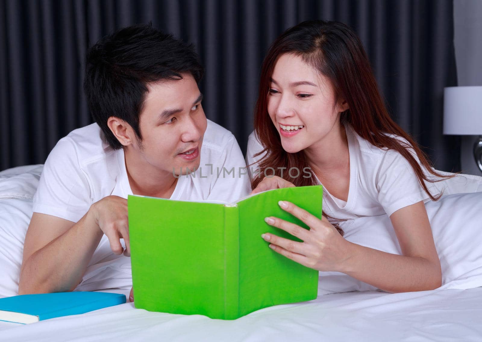 young couple reading a book on bed in bedroom by geargodz