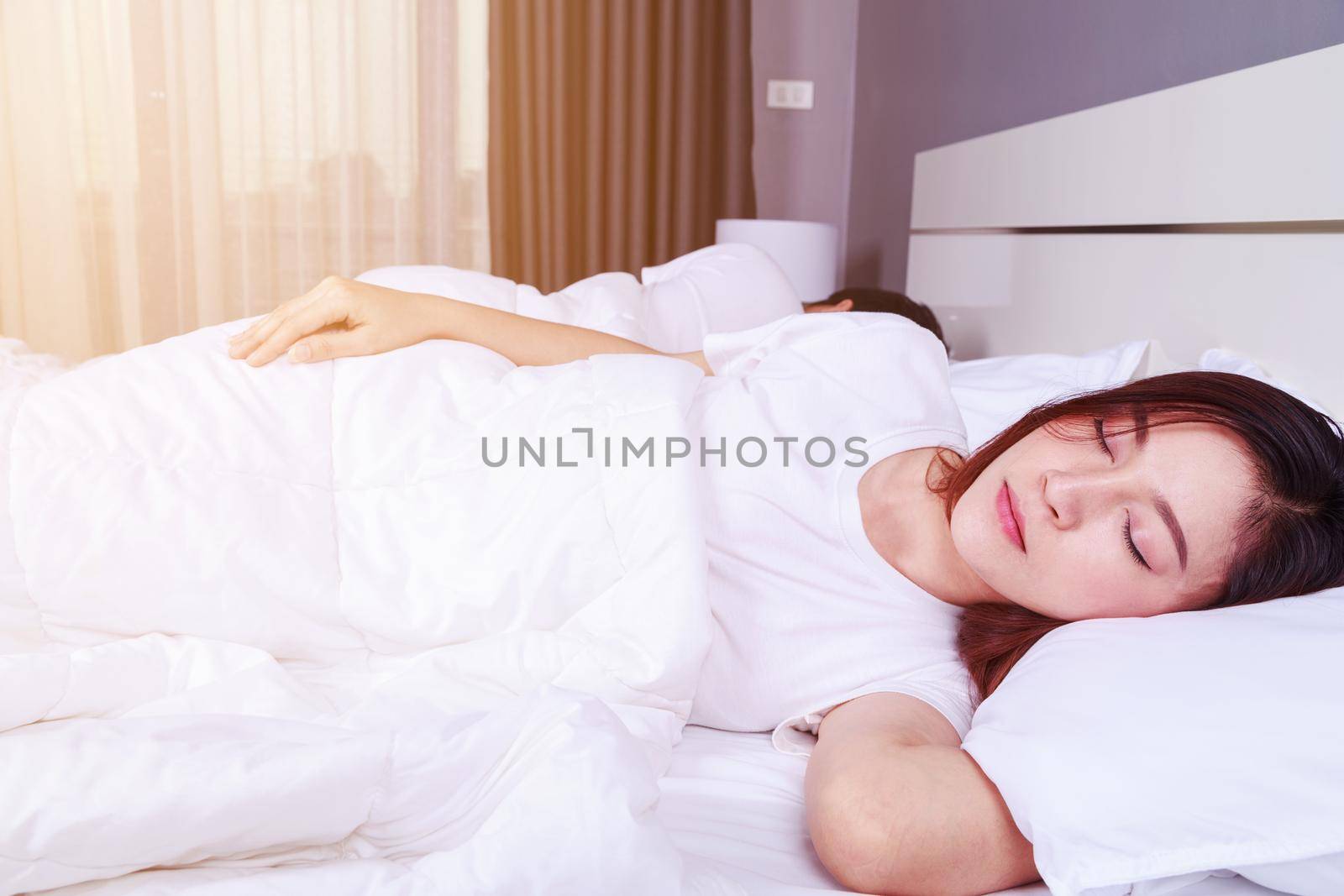 young woman sleeping with her husband in a comfortable bed at home