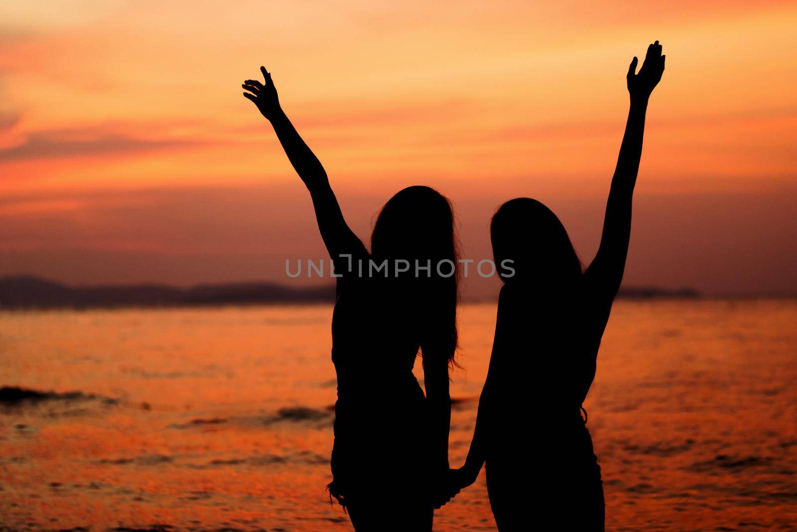 Silhouette of two woman having fun on the sea beach by geargodz
