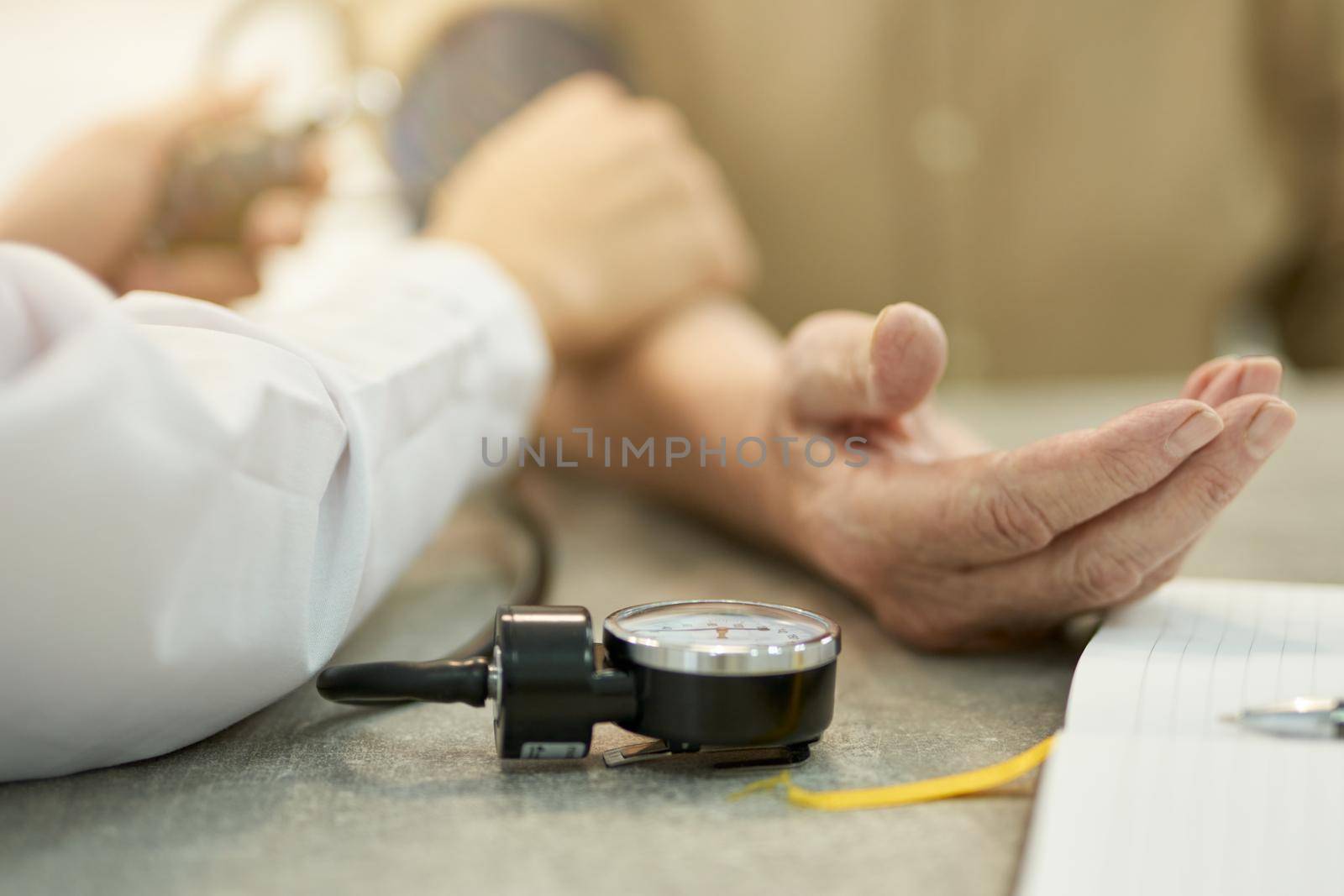 Professional doctor measuring heart-rate and blood pressure of aged person by friendsstock