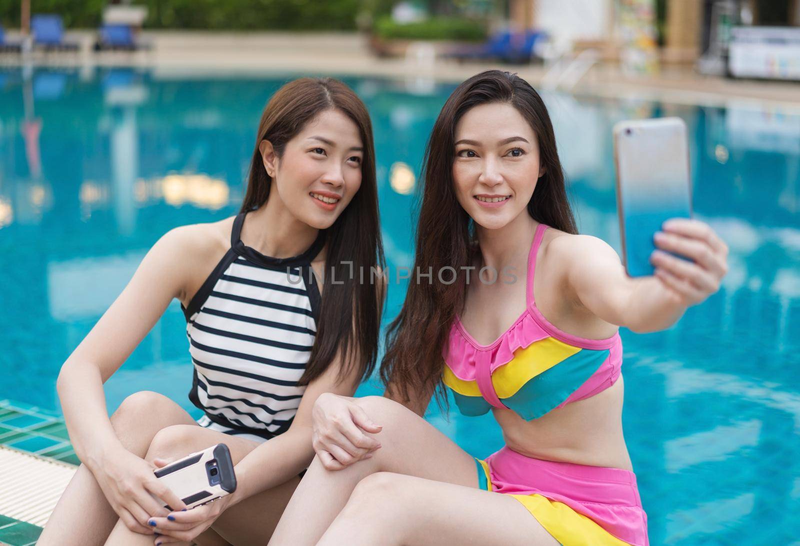 woman in swimsuit making selfie photo on smartphone in the swimming pool