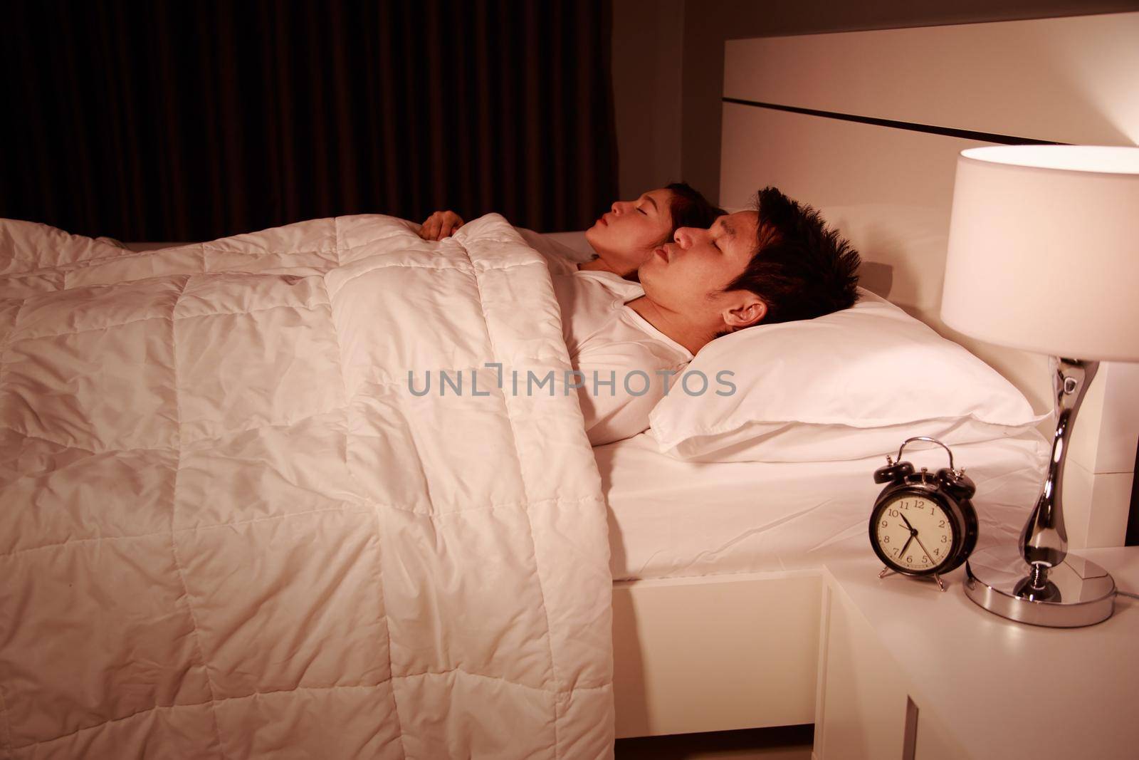 young couple sleeping on a comfortable bed in bedroom at night