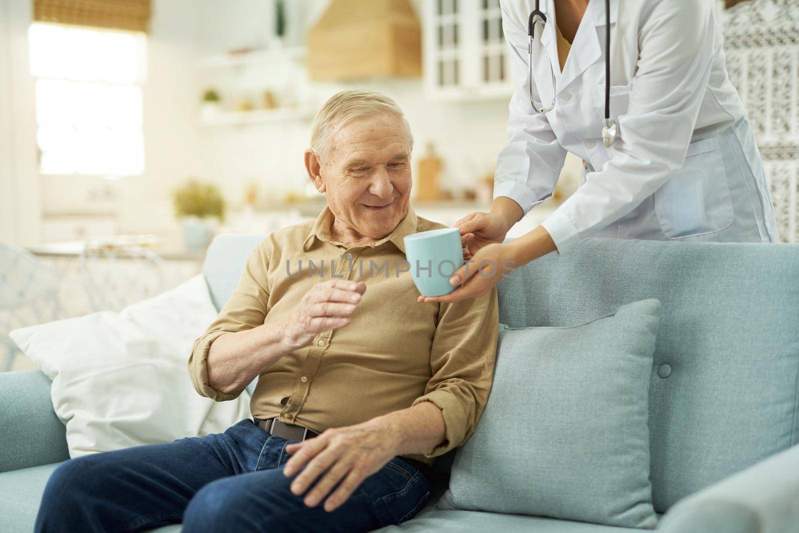 Elderly man going to drink a hot drink at home by friendsstock