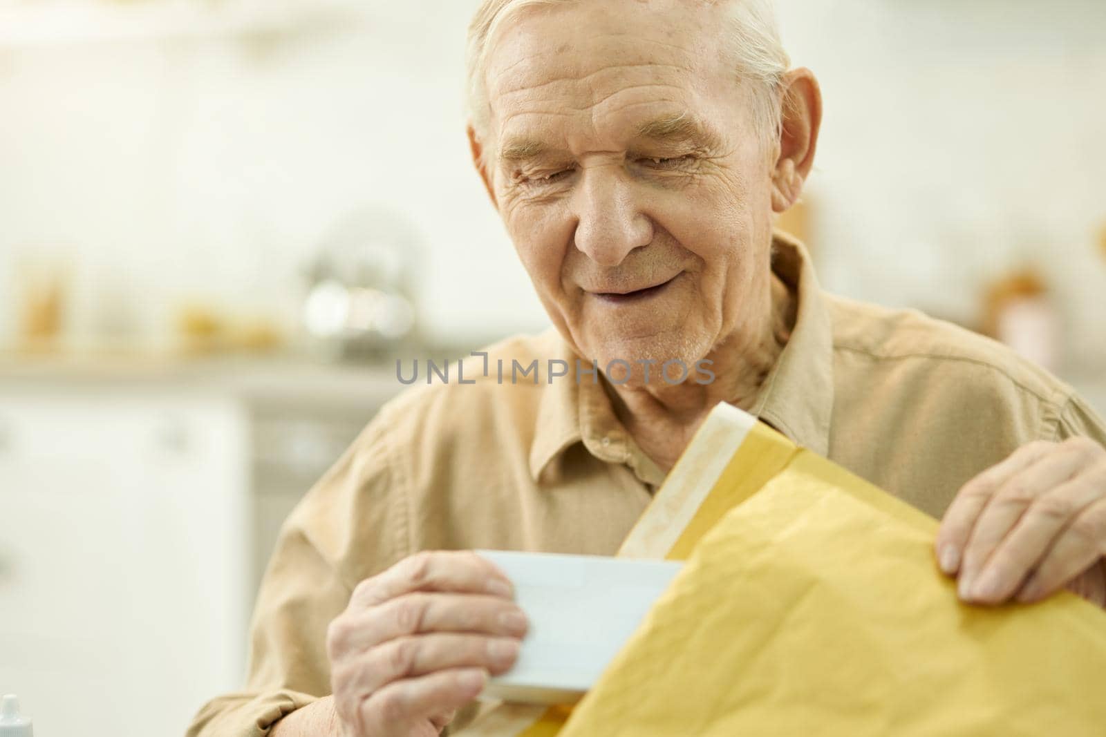 Elderly man unpacking a postal parcel at home by friendsstock