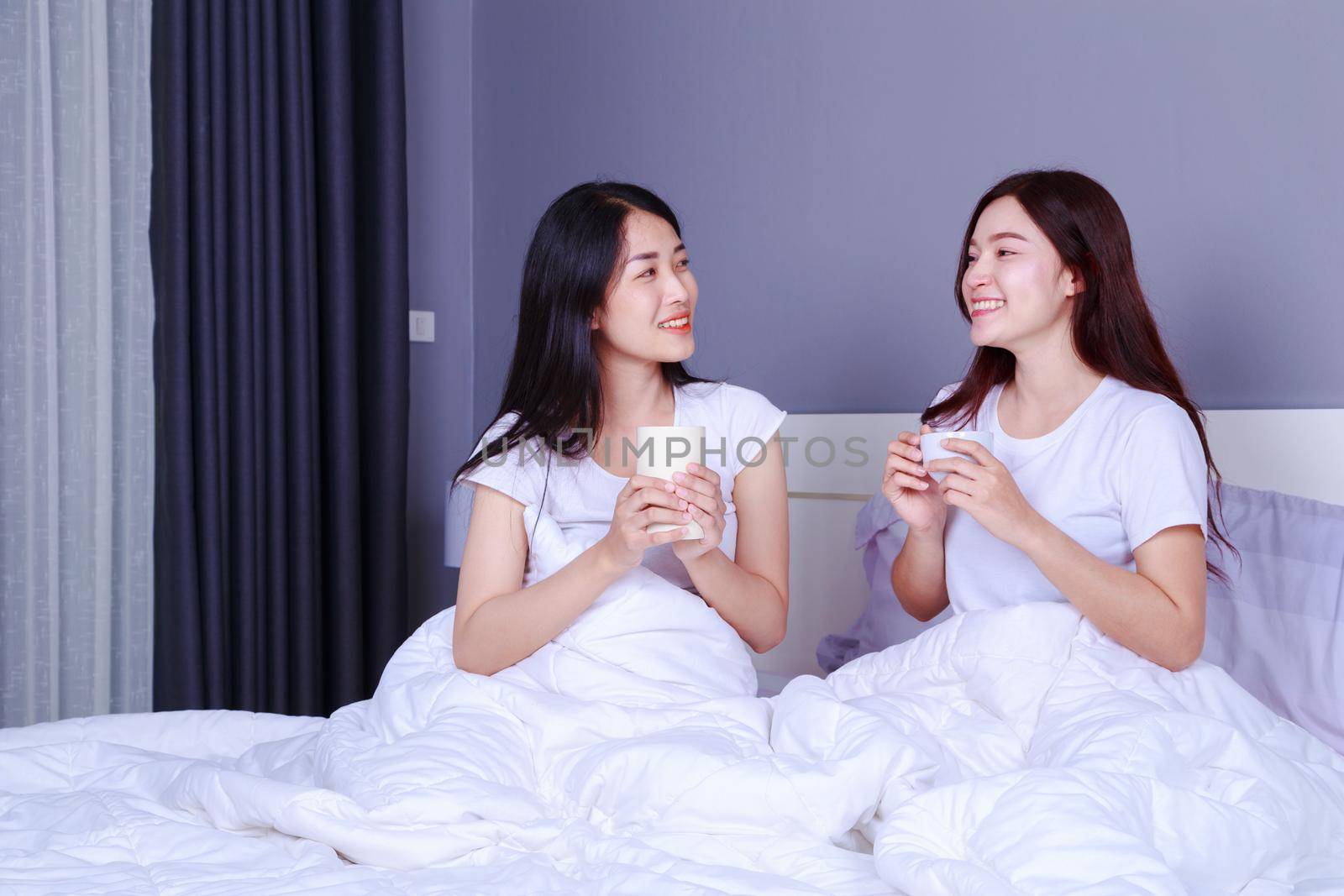 two best friends talking and drinking a cup of coffee on bed in bedroom  by geargodz