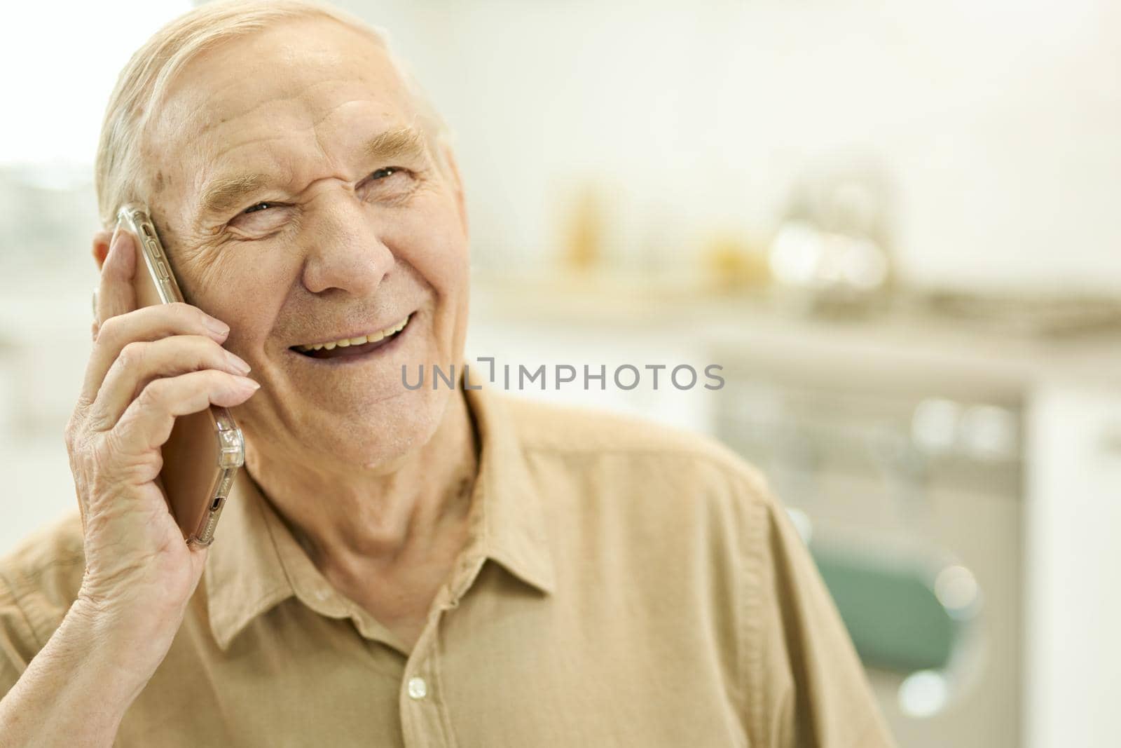 Copy-space photo of an excited senior man smiling and talking on the phone while staying home