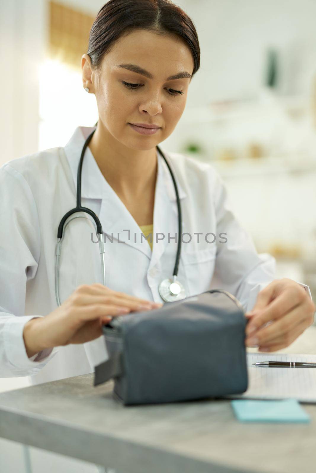 Waist-up photo of a concentrated female doctor packing up manometer into a convenient case