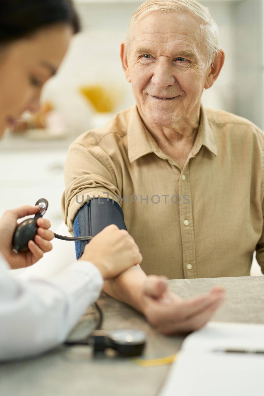 Thankful aged gentleman having his blood pressure checked by friendsstock