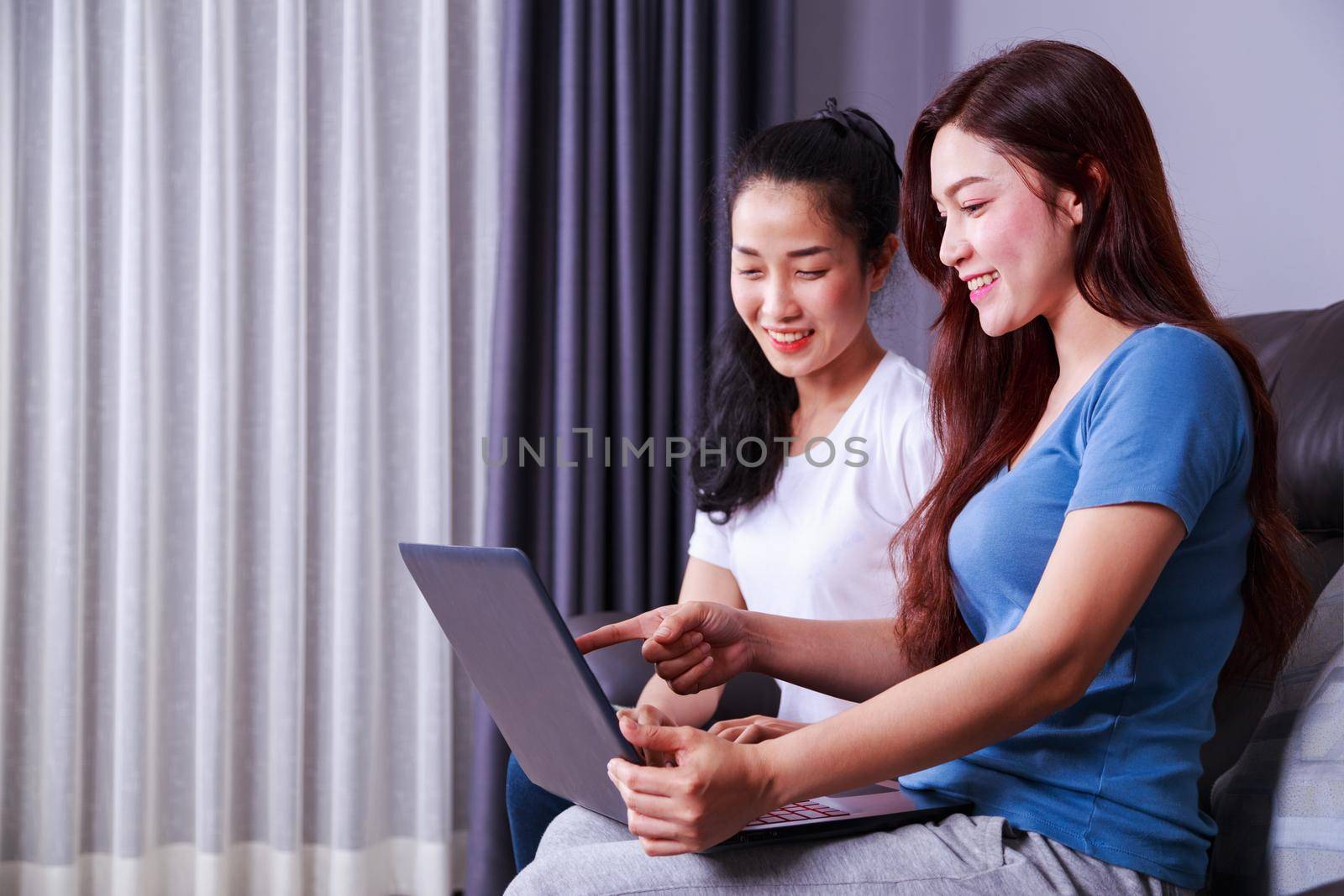 two woman using a laptop computer on sofa in living room at home by geargodz