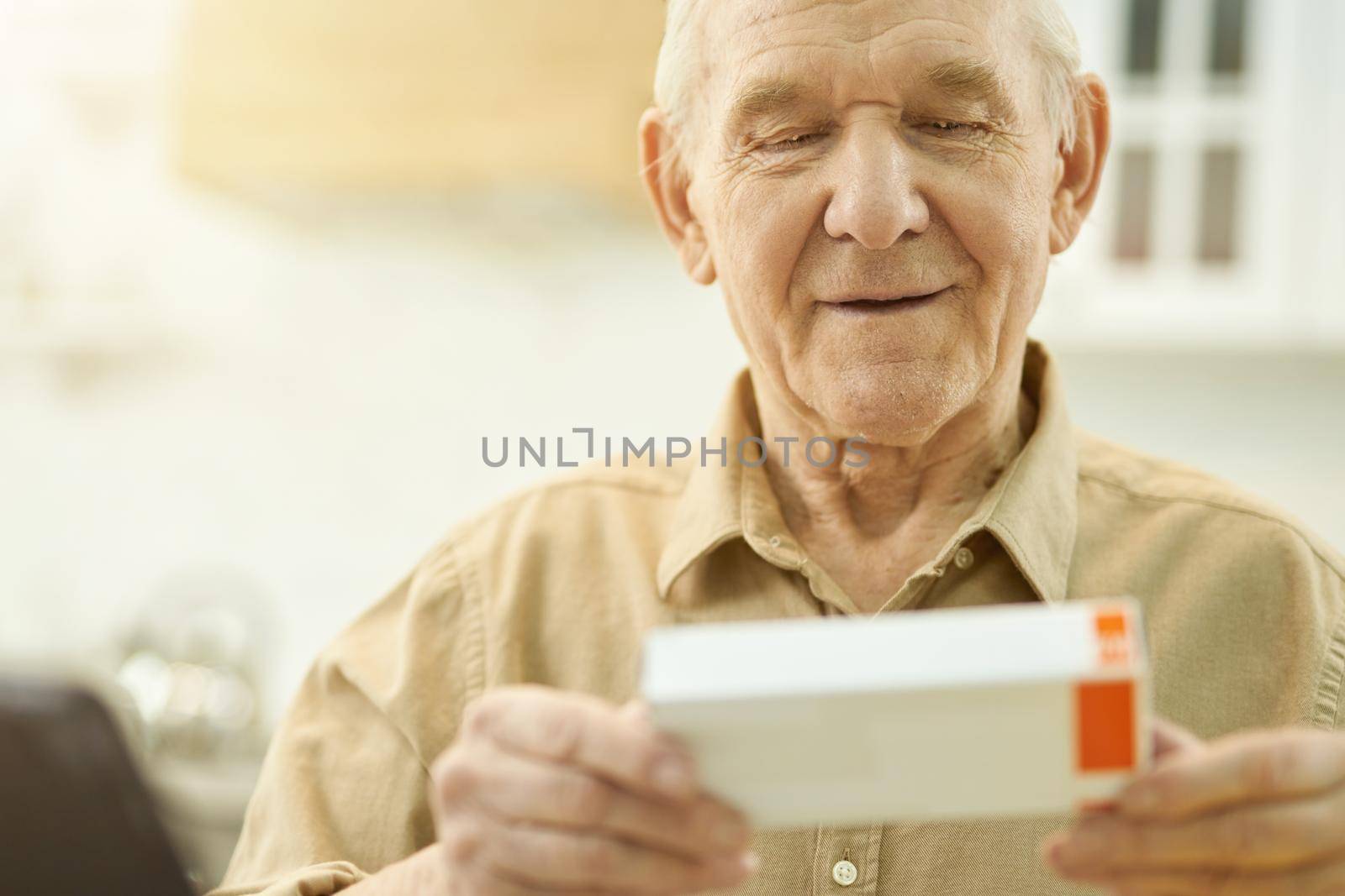 Copy space photo of elderly man looking at a tiny box of medication in his hands