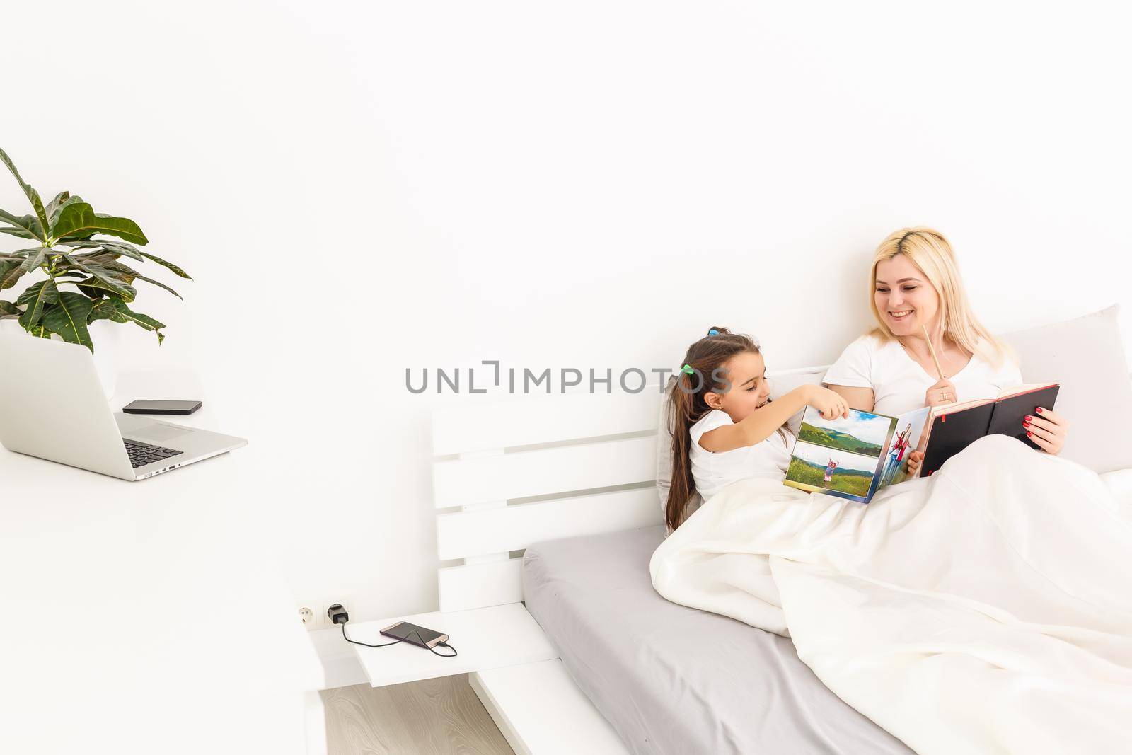 mother and daughter in bed watching a photo book