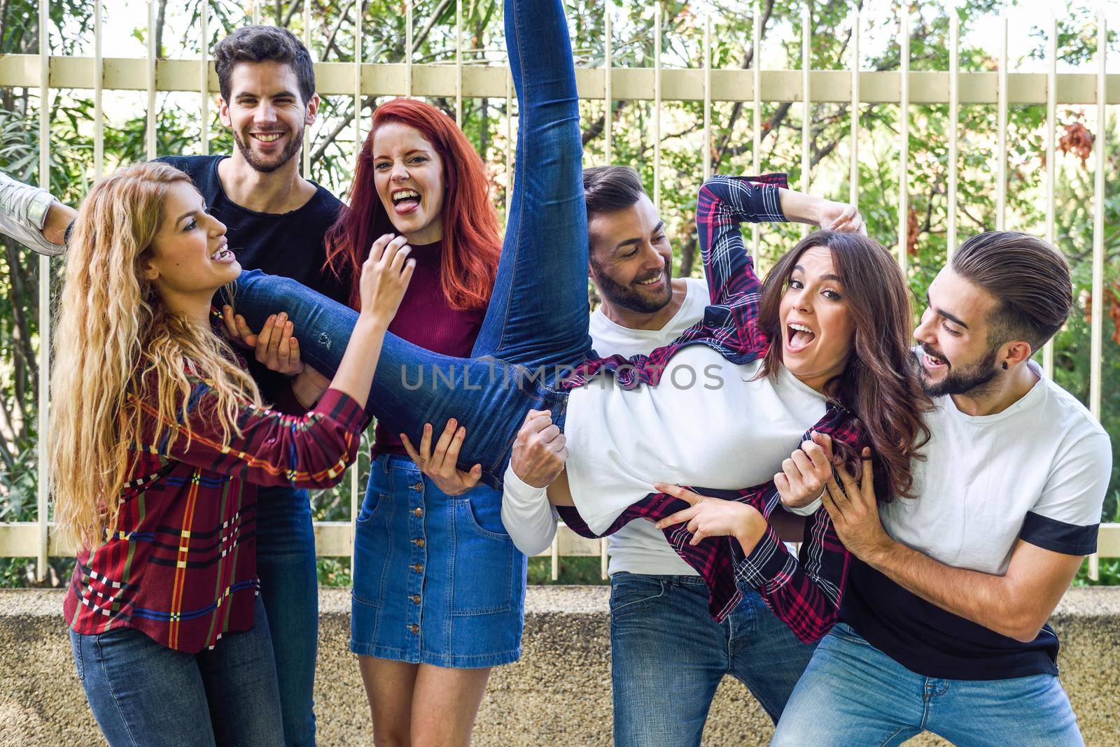 Group portrait of boys and girls with colorful fashionable clothes holding friend. Urban style people having fun - Concepts about youth and togetherness.