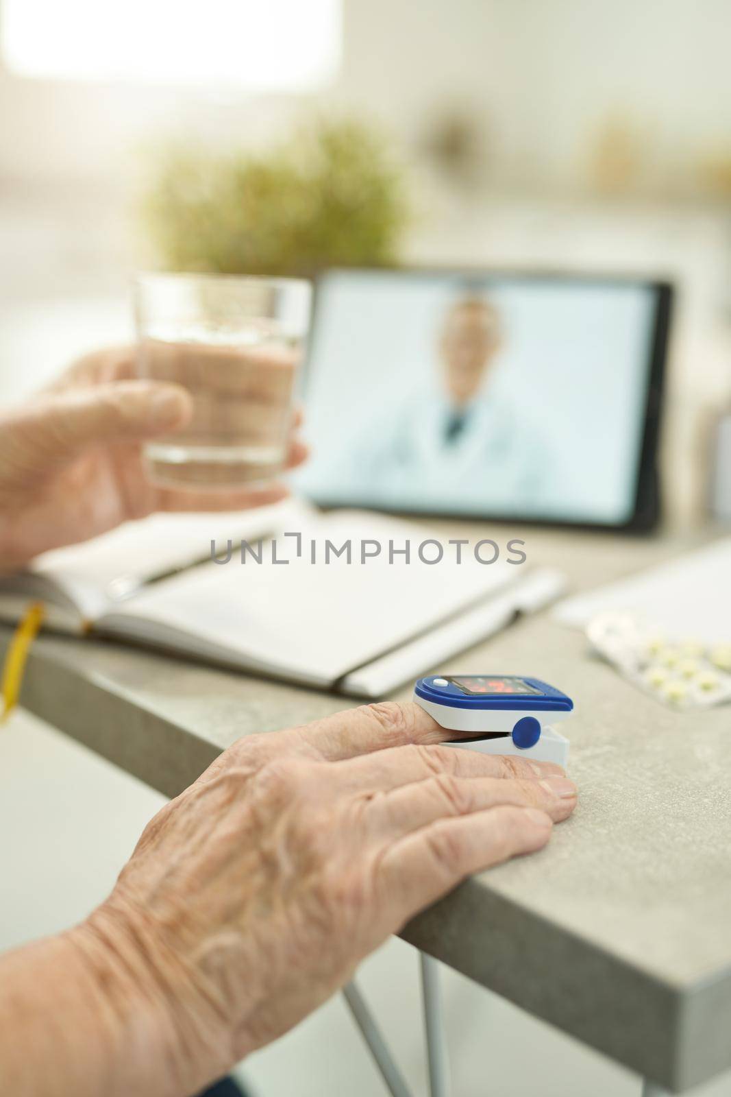 Cropped photo of aged man measuring his pulse and oxygen before reporting to doctor on a video-call