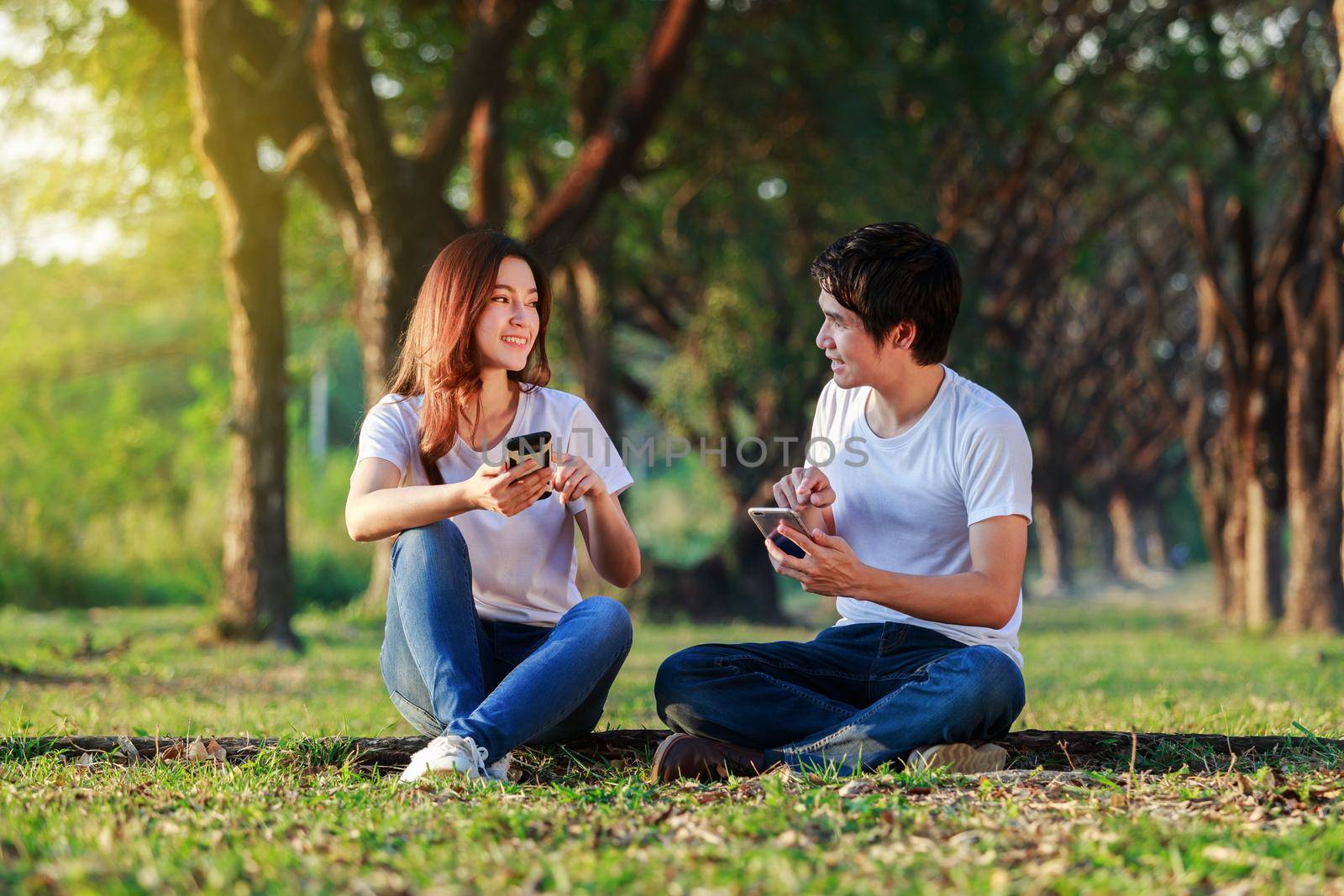 couple using mobile phone and talking in park by geargodz