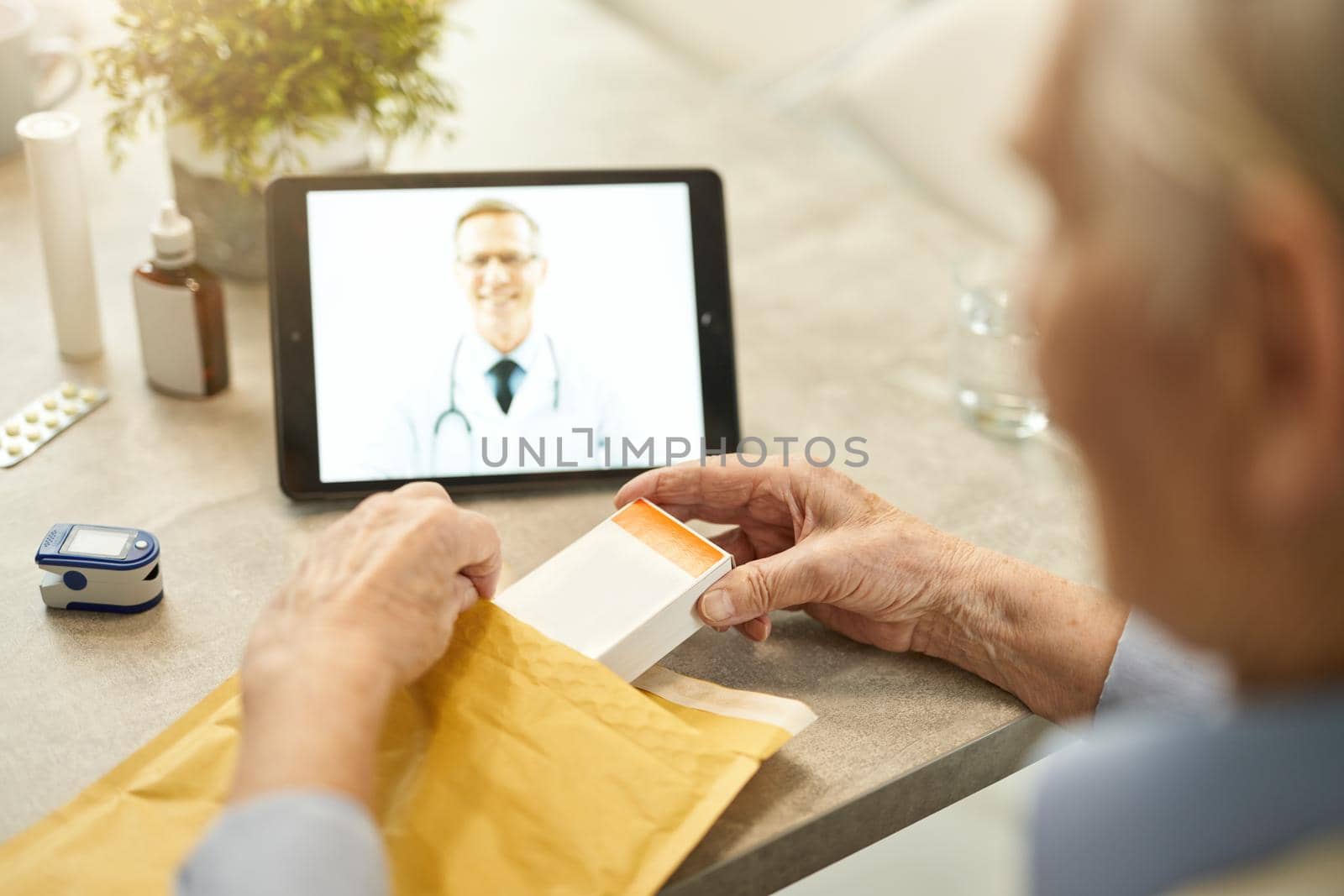 Aged gentleman taking a pack of pills out of parcel by friendsstock