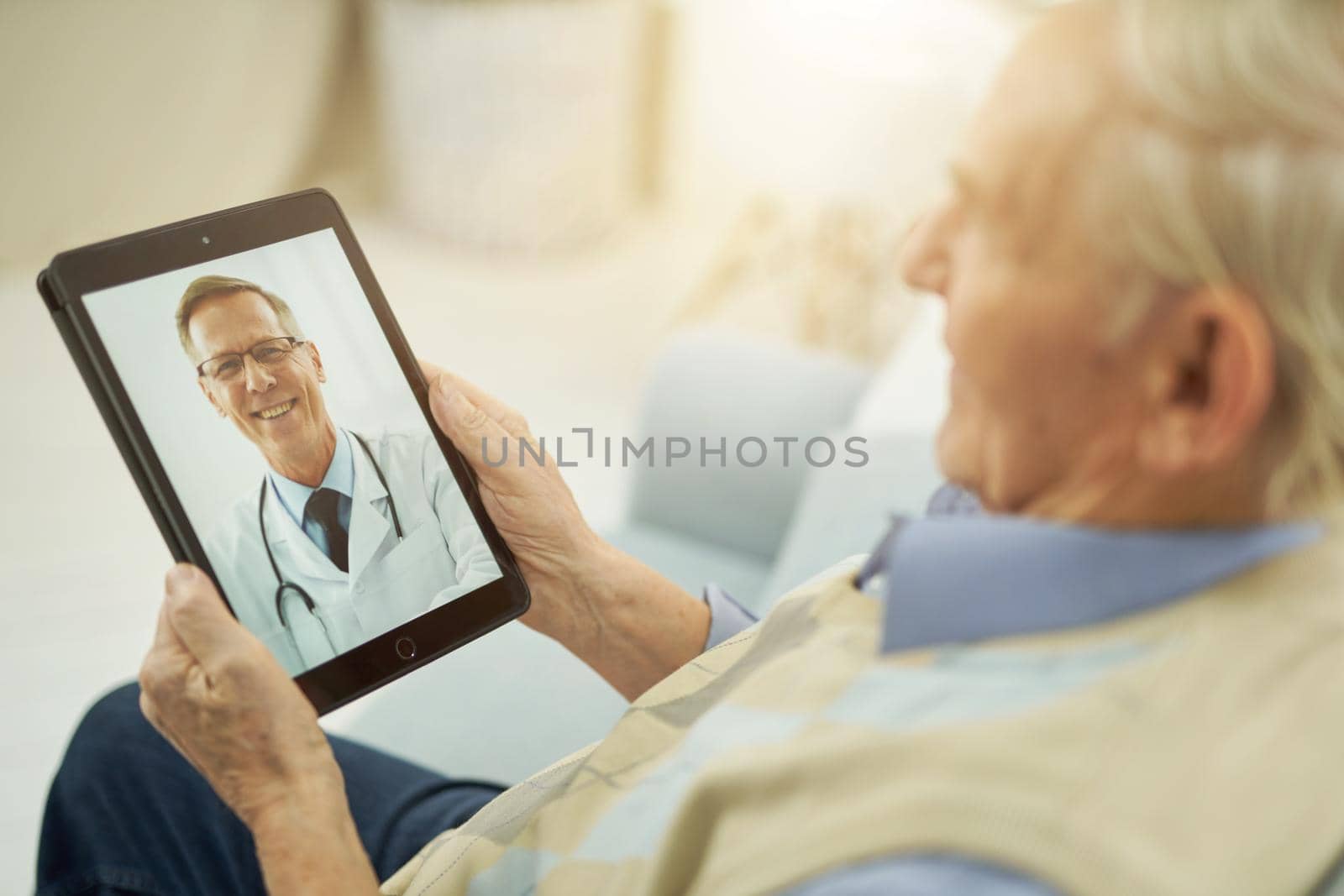 Gray-haired man during an online consultation with a doctor while sitting at home by friendsstock