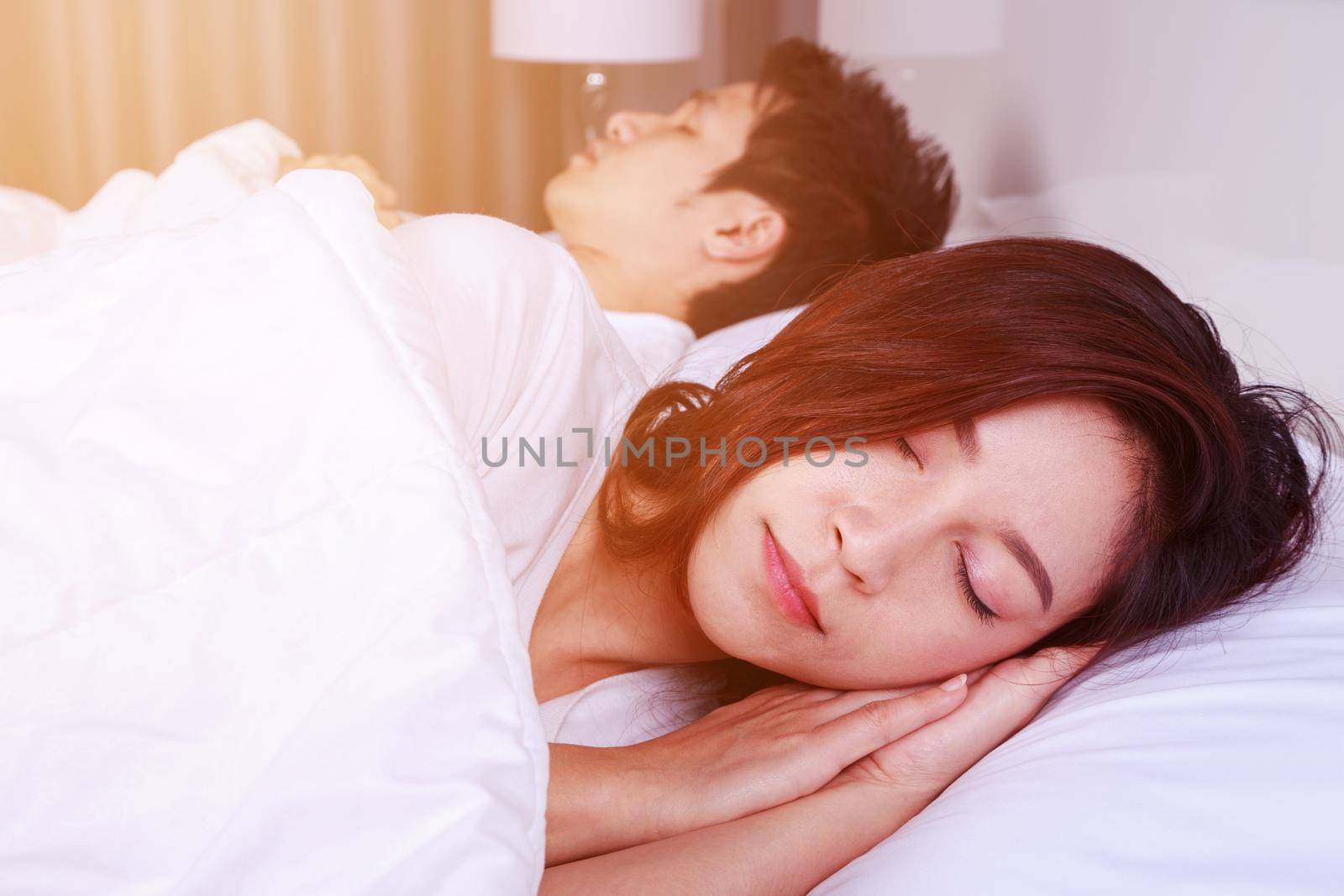 young woman sleeping with her husband in a comfortable bed at home