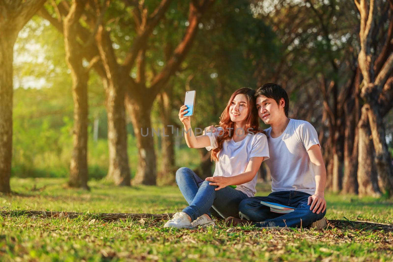 couple using mobile phone taking a selfie in the park by geargodz