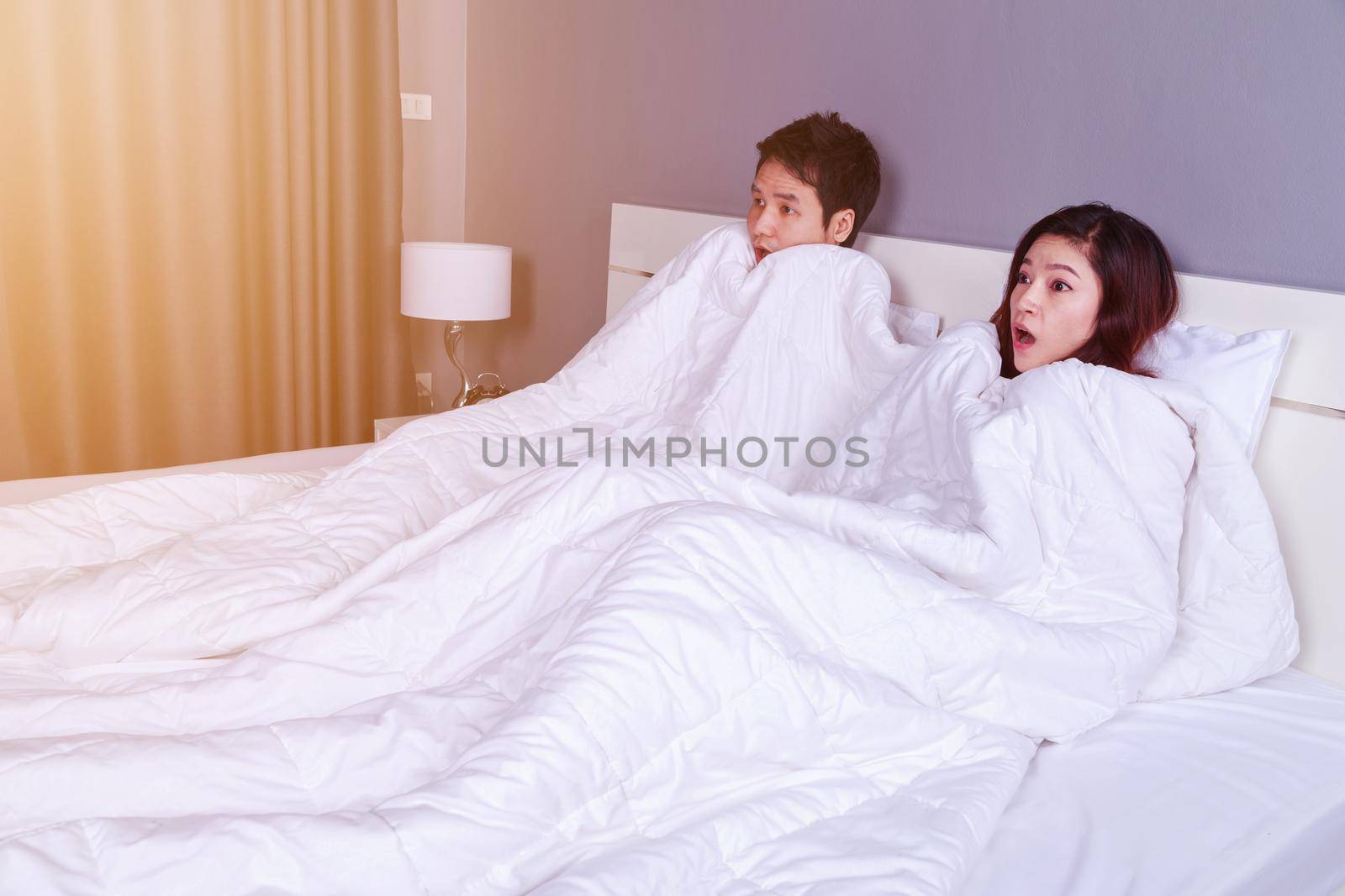 couple watching scared movie under the blanket on bed by geargodz