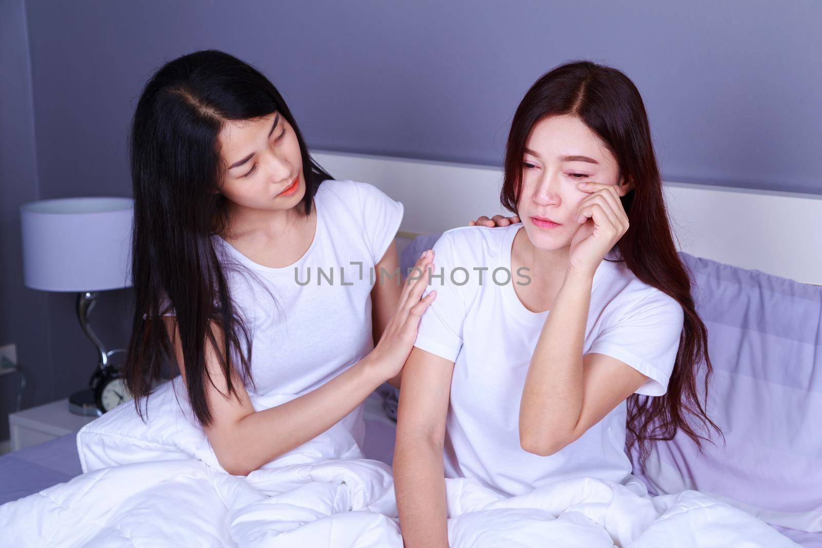 woman having problem and woman cheers her up on bed in bedroom by geargodz