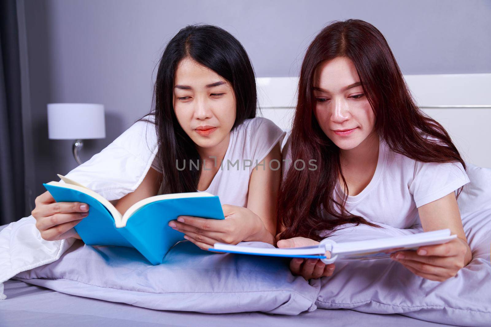two woman reading a book on bed in the bedroom
