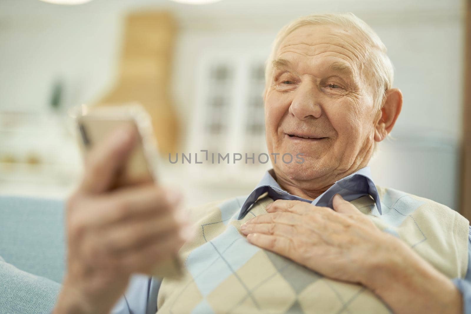 Happy old-aged man enjoying the conversation on the phone online at home