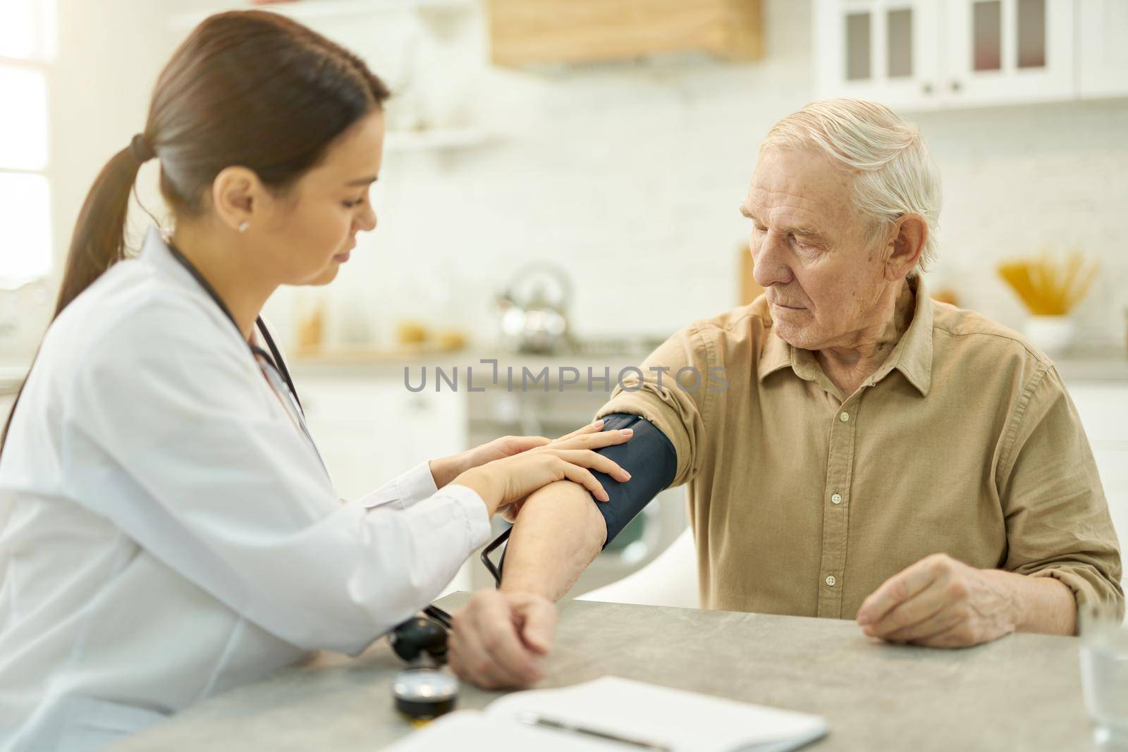 Mindful doctor securing manometer cuff around upper arm of a senior patient while visiting him in his home