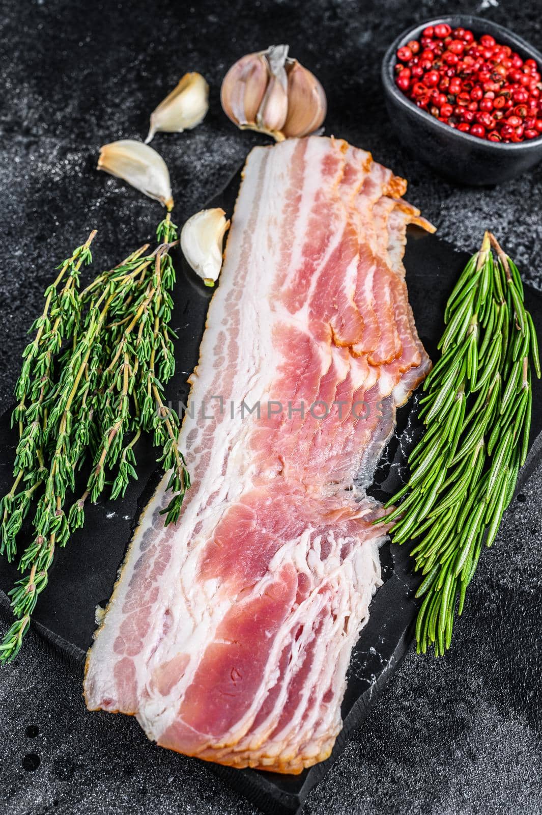 Raw sliced pork bacon ready for cooking. Black background. Top view.