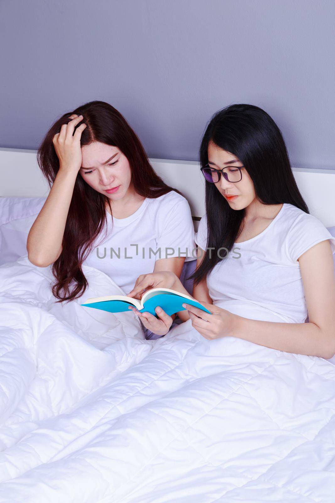 two woman reading a book on bed in the bedroom