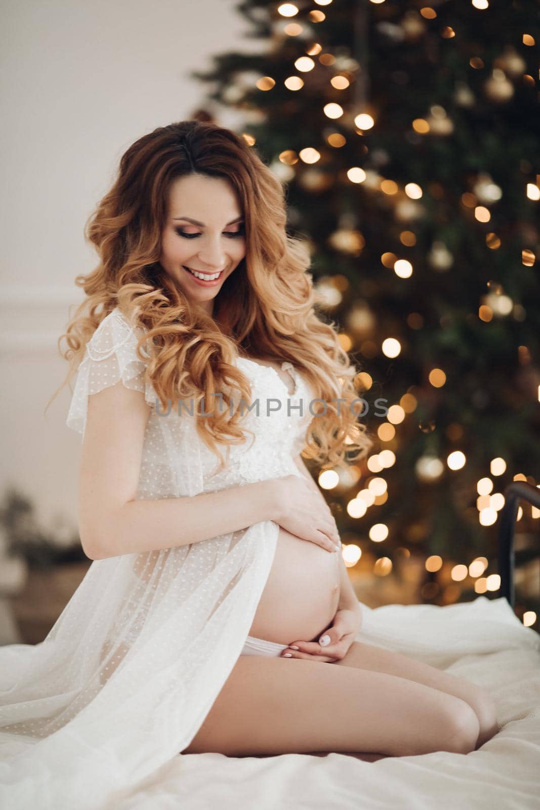 Portrait of smiling pregnant young woman tenderness holding big tummy showing heart by StudioLucky