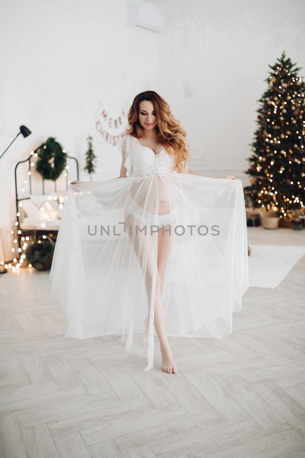 Beautiful pregnant woman standing in the studio with New Year decorations by StudioLucky