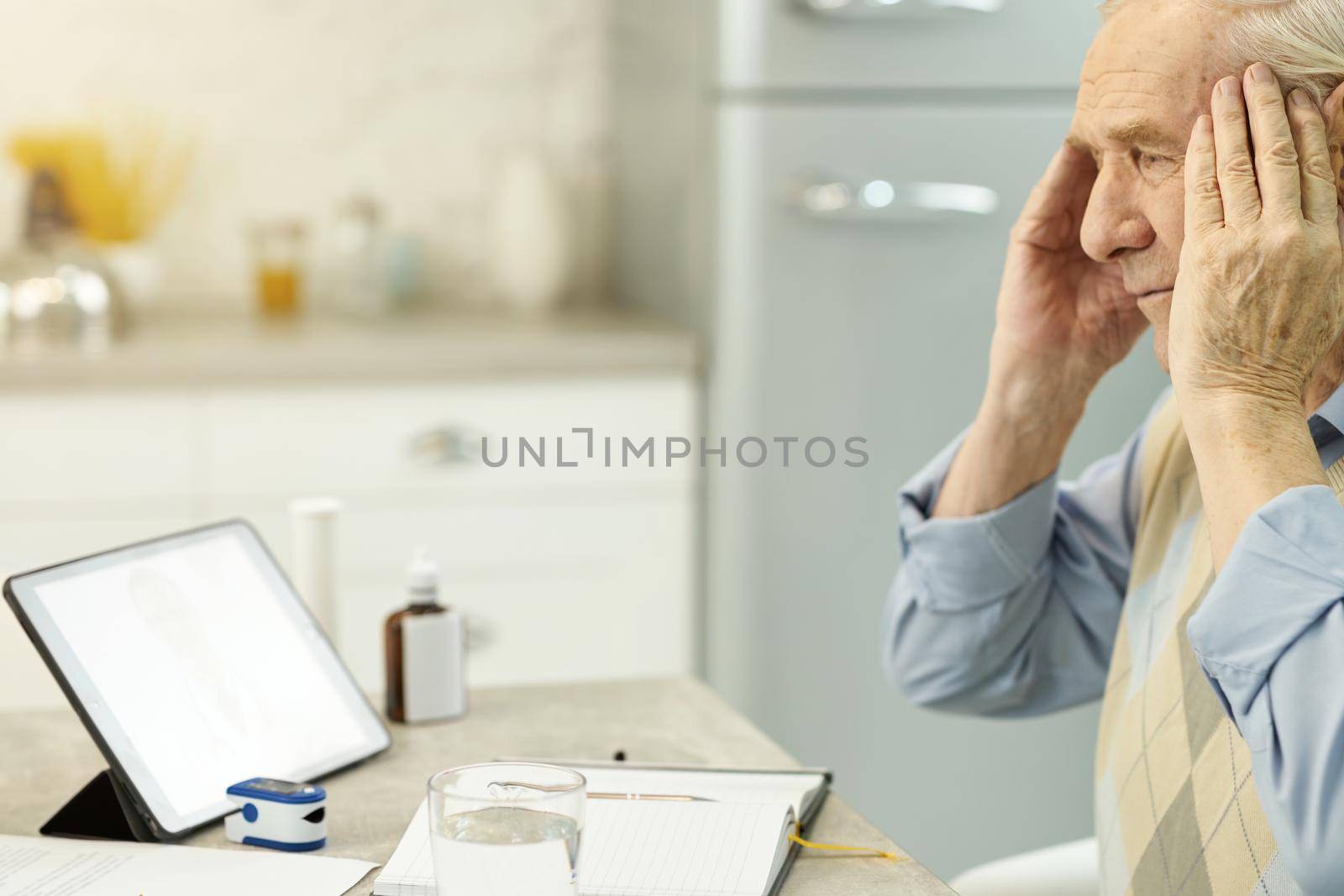 Worried aged man having headache and consulting online medic by friendsstock