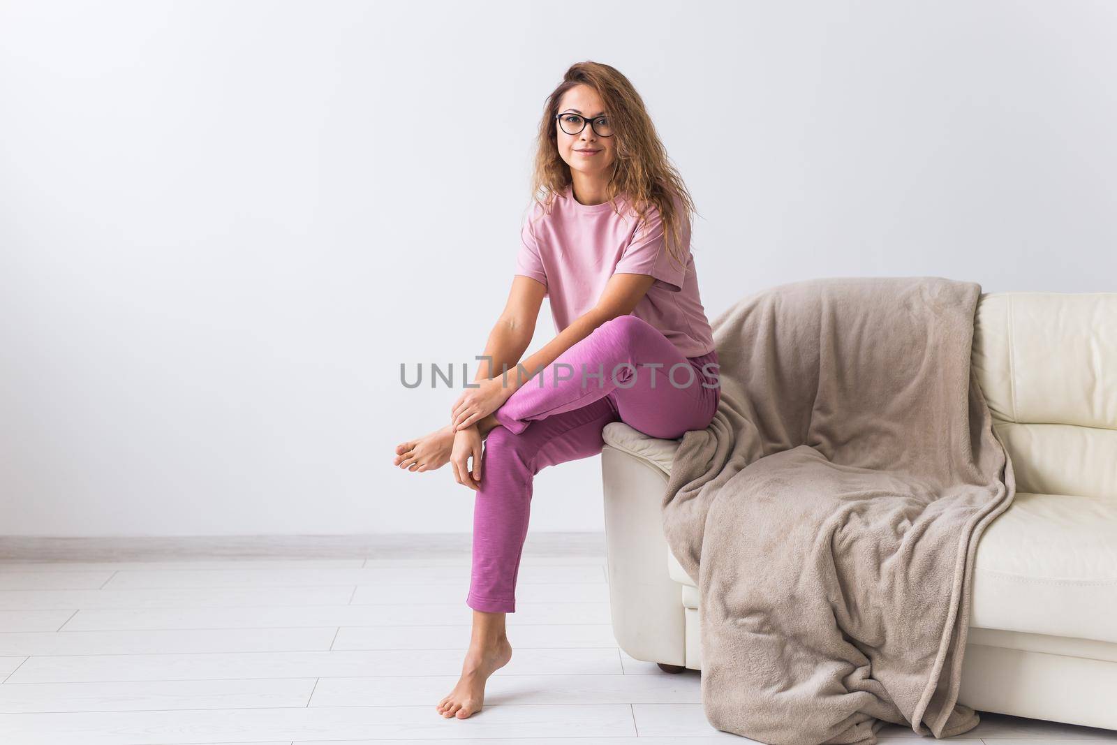 Young attractive woman dressed in beautiful colorful pajama posing as a model in her living room. Comfortable sleepwear, home relaxation and female fashion concept. by Satura86