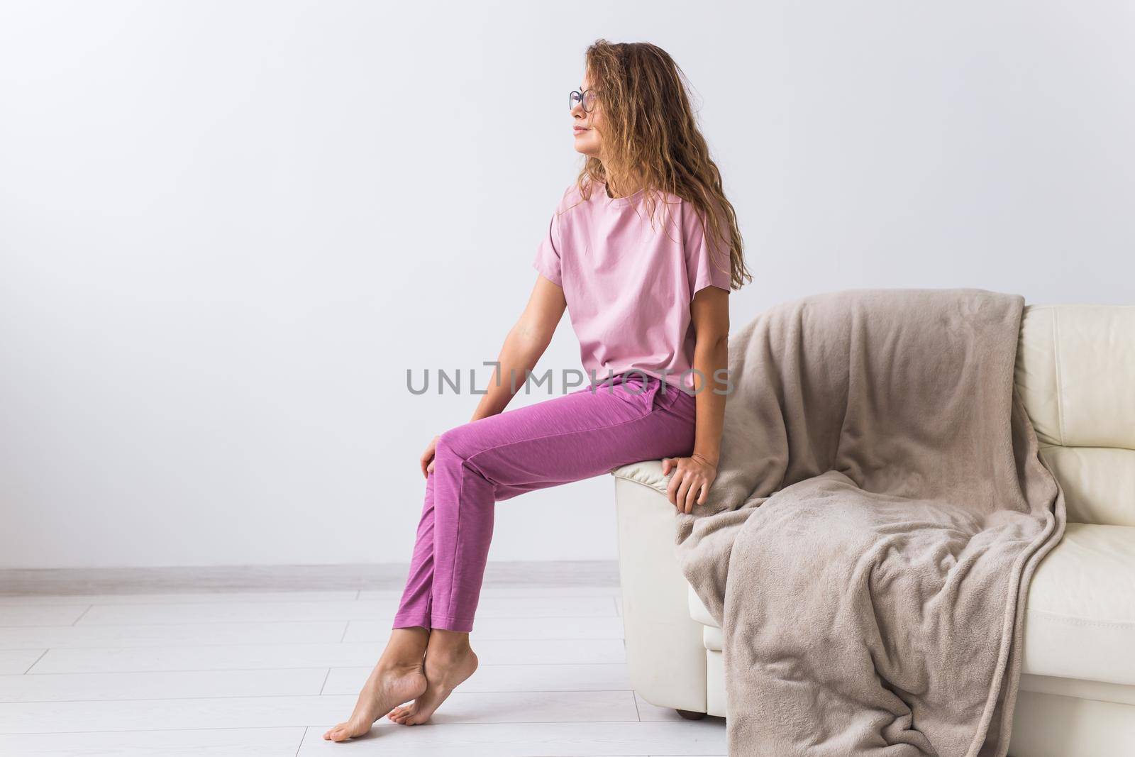 Young attractive woman dressed in beautiful colorful pajama posing as a model in her living room. Comfortable sleepwear, home relaxation and female fashion concept. by Satura86