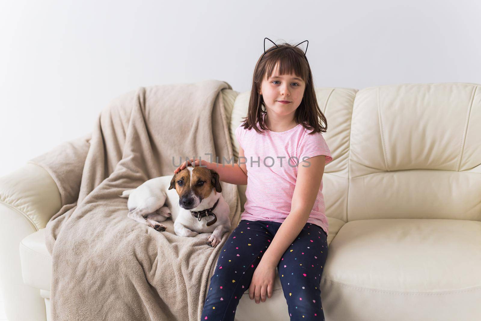 Child girl with cute dog jack russell terrier on the couch. Pets , children and home concept. by Satura86