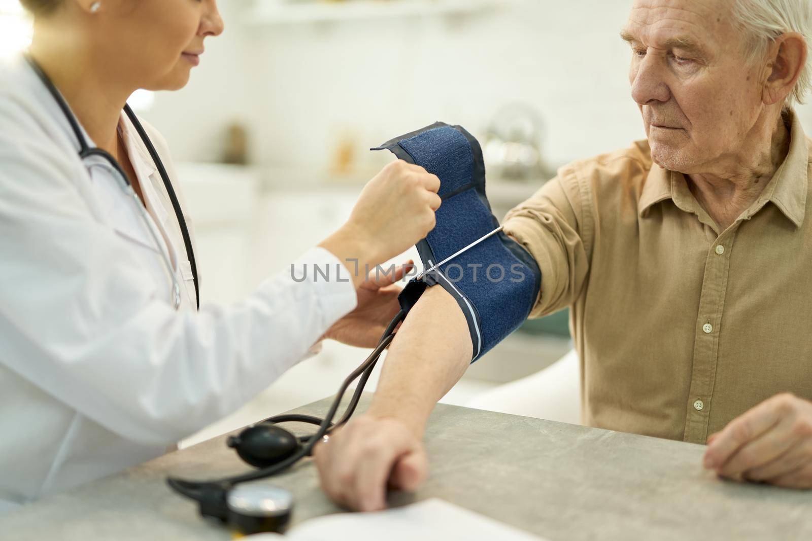 Aged man with manometer cuff around his arm by friendsstock