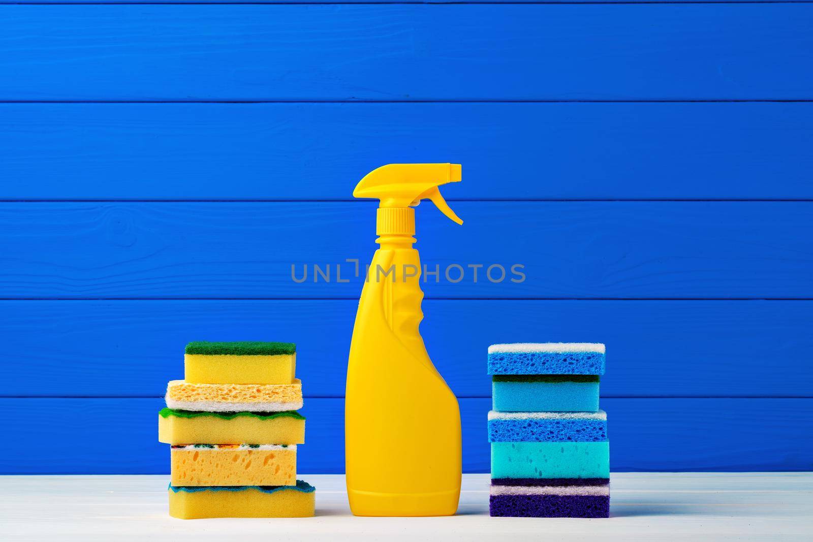 Stack of new cleaning sponges and liquid detergent against blue wooden background by Fabrikasimf