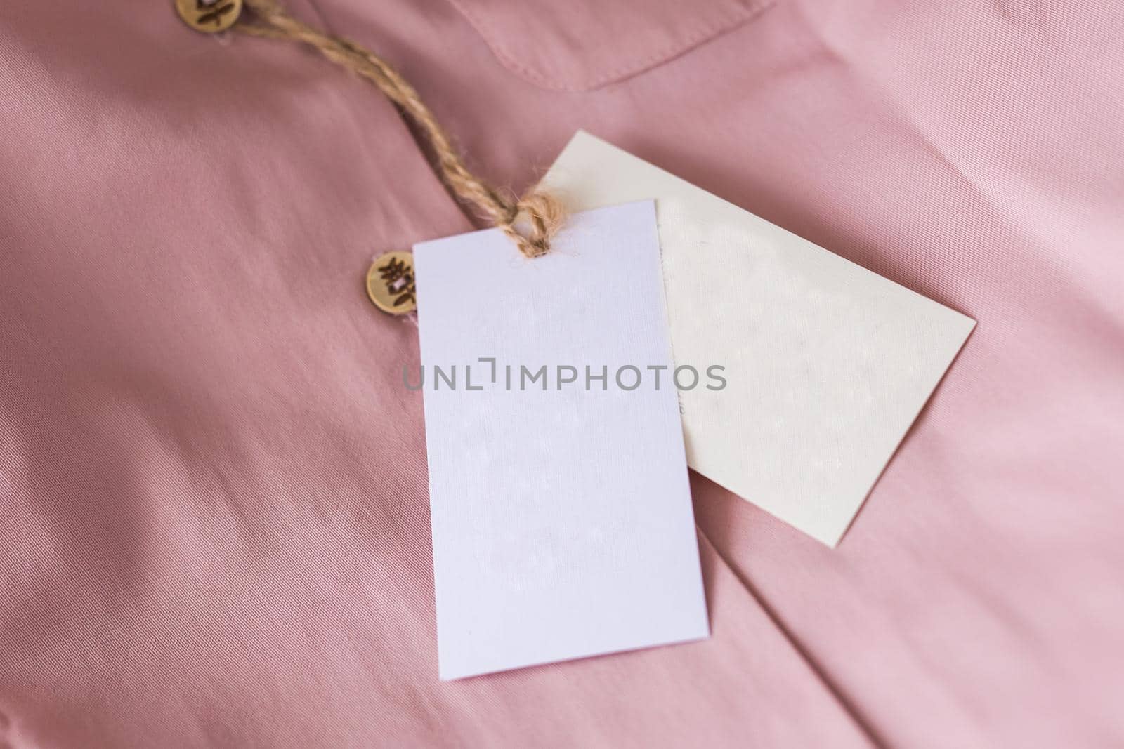 Close-up blank tag label on pink shirt. Copy space