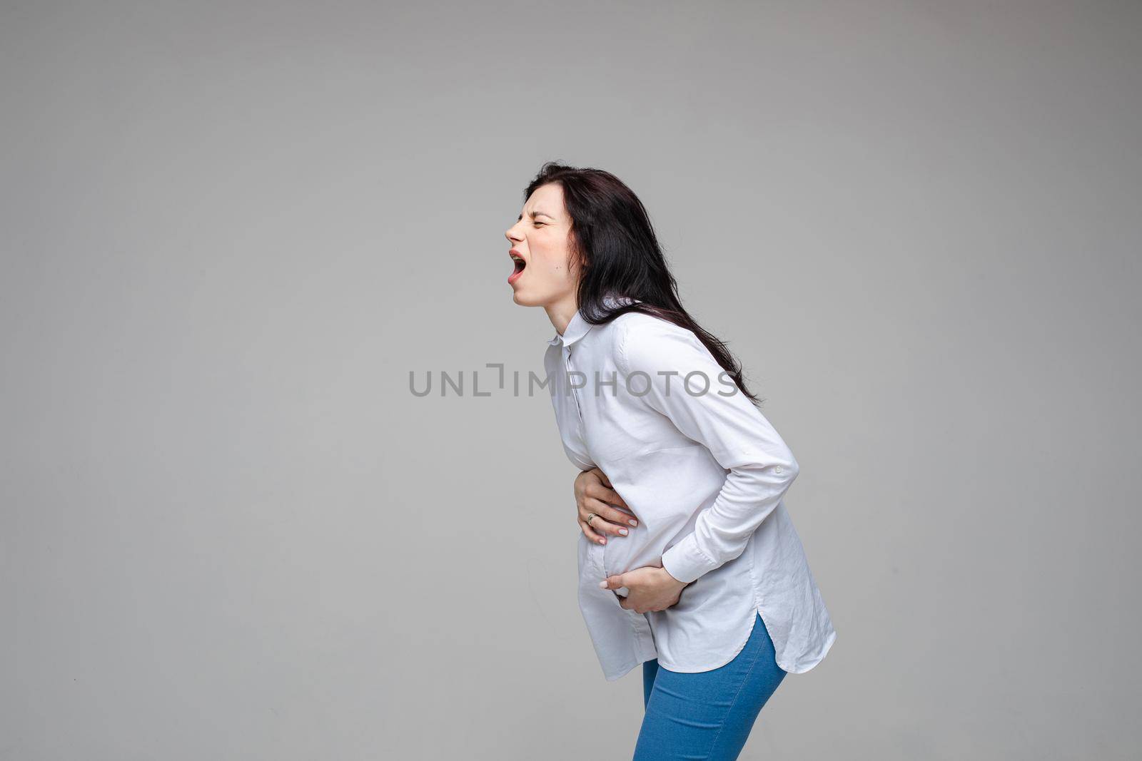 young caucasian pregnant female with dark hair screaming and giving birth to a baby