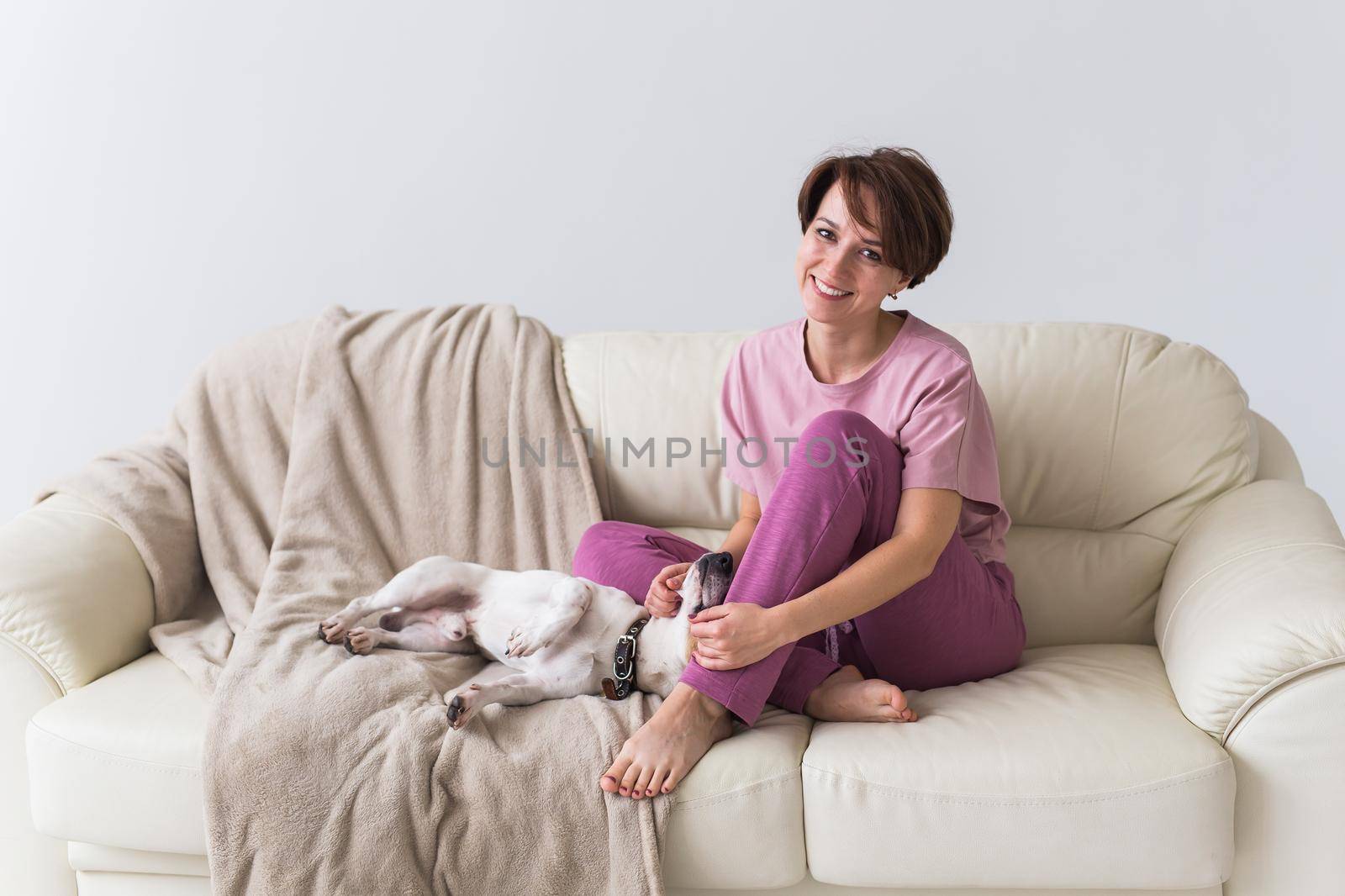 Young beautiful woman at home with her cute dog. Quarantine, isolation, coronavirus pandemic world. Stay at home. by Satura86