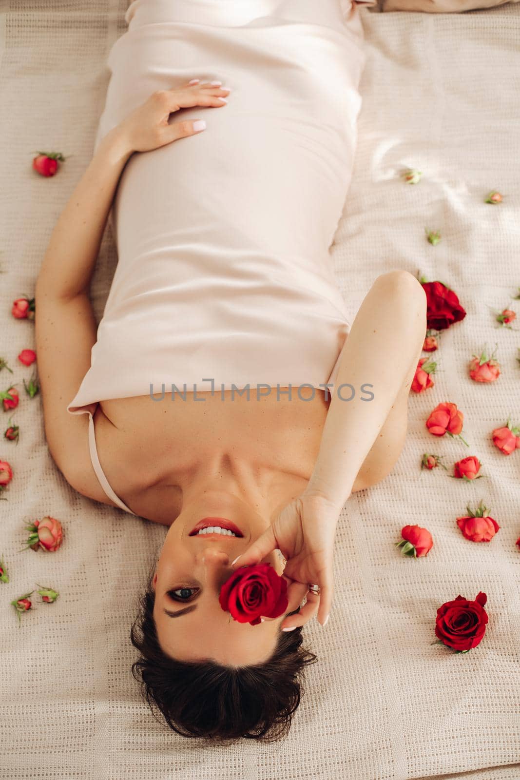 cheerful pregnant woman lies on the sofa with a lot of flowers around her