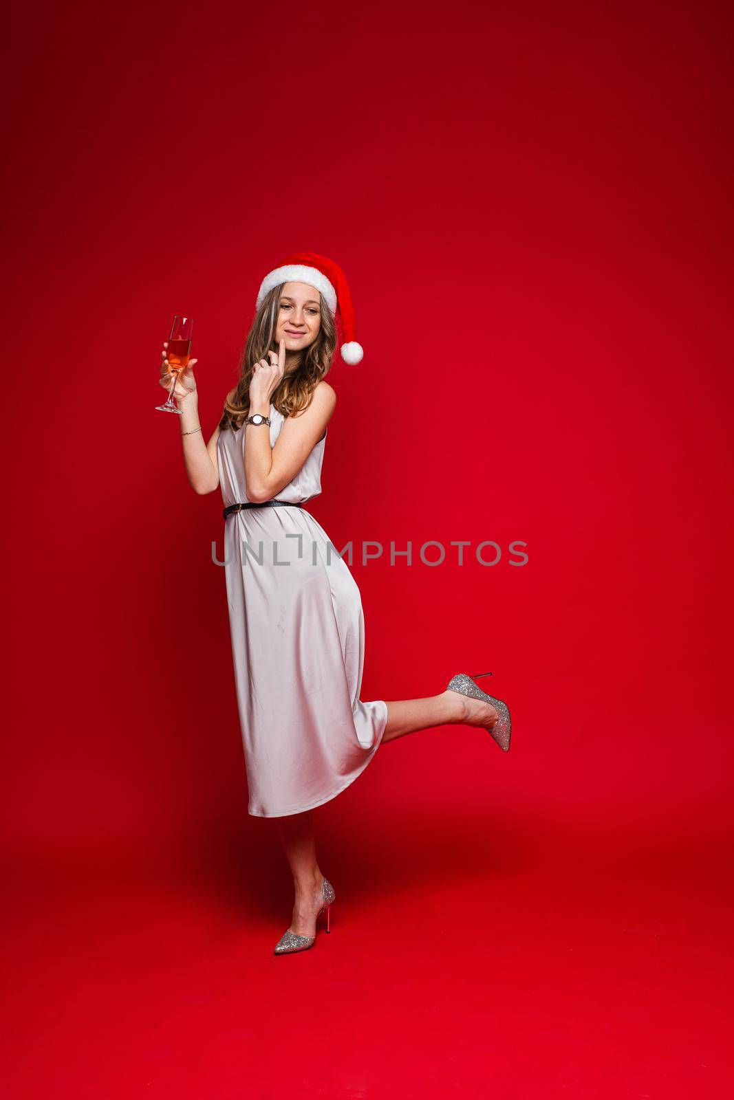 caucasian woman with attractive appearance holds a glass of white wine, picture isolated on red background