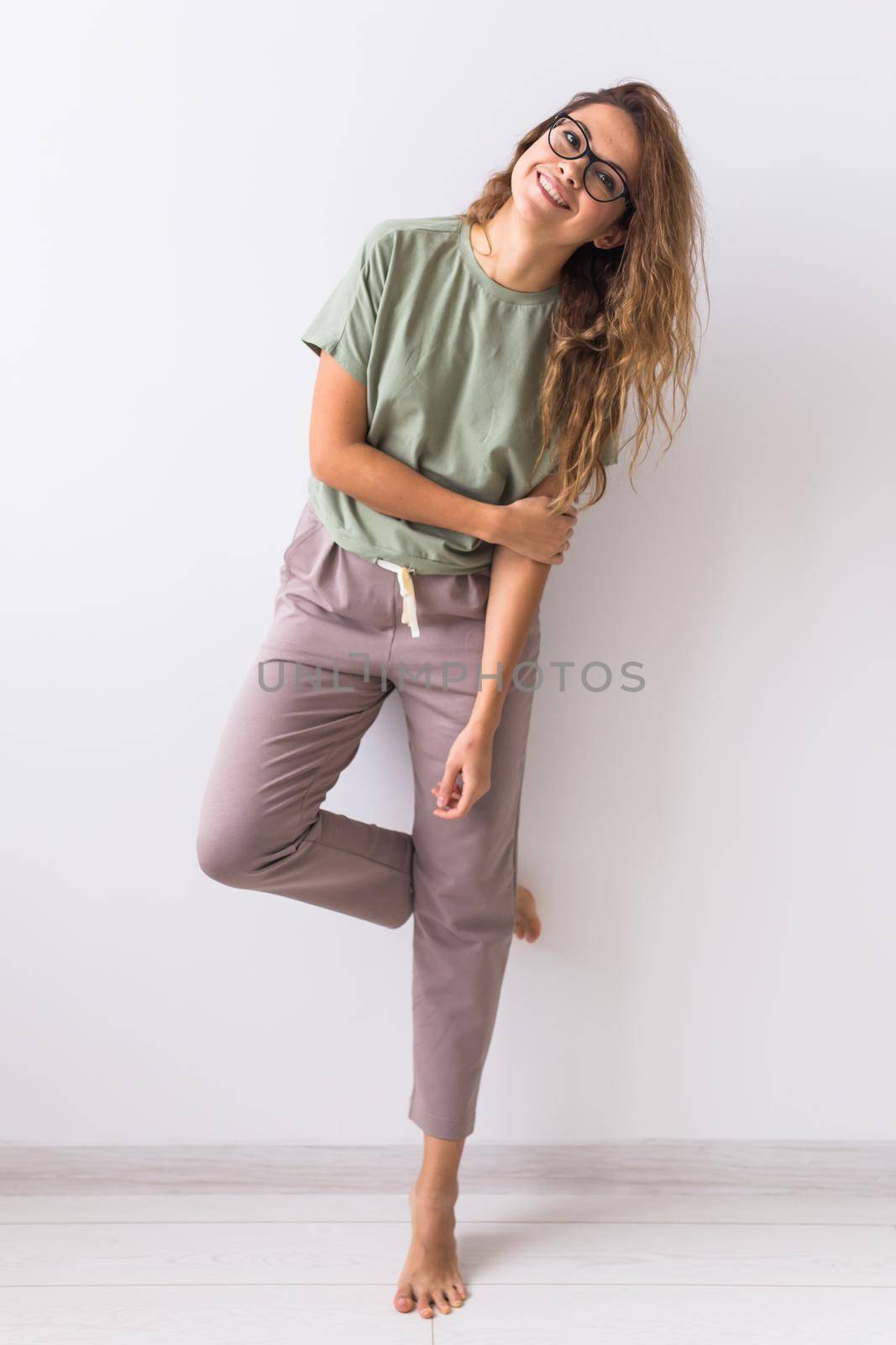 Young attractive woman dressed in beautiful colorful pajama posing as a model in her living room. Comfortable sleepwear, home relaxation and female fashion concept