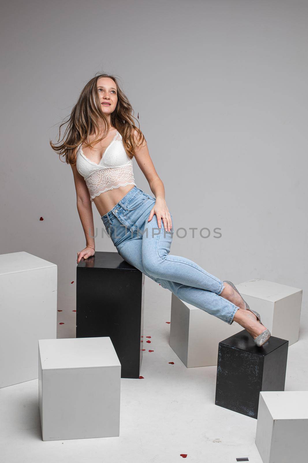 Pretty young woman lying on black boxes, isolated on grey background. Copy space. Lifestyle concept