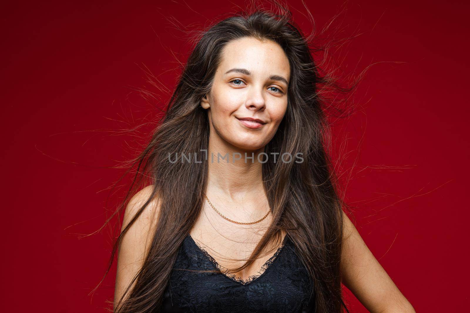 Head shot of long haired smiling brunette young joyful female with healthy hairs on red background with copy space by StudioLucky