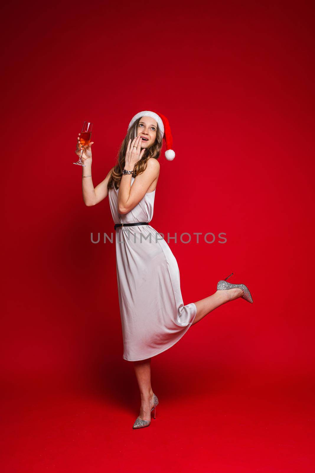 caucasian woman with attractive appearance holds a glass of white wine, picture isolated on red background