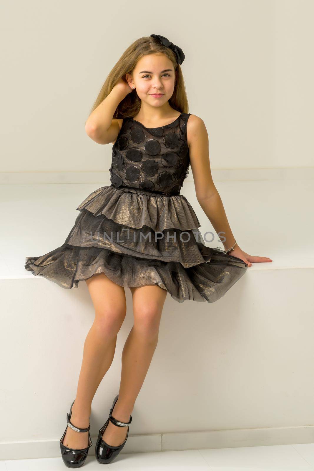 Beautiful Girl Sitting on Ledge of the Wall and Smiling at Camera, Portrait of Pretty Blonde Teenage Girl in Stylish Clothing Posing in Studio